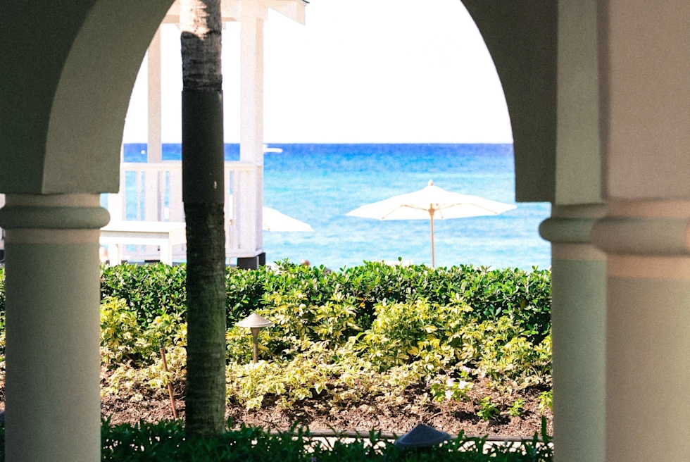 arched column pathway to a beach club with white umbrellas