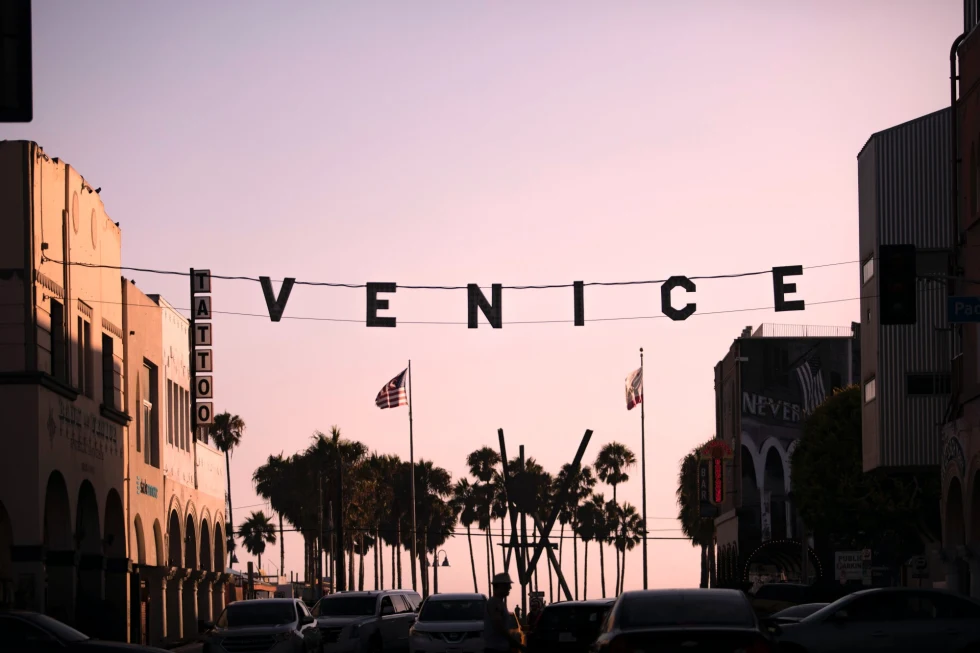 hanging sign over a street at sunset that reads "Venice"