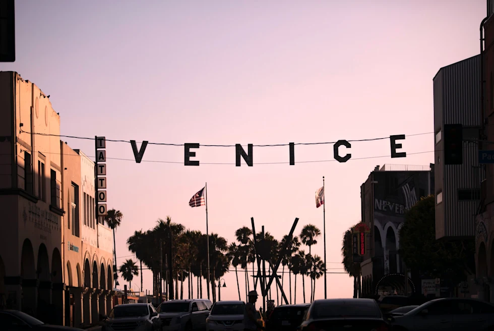 hanging sign over a street at sunset that reads "Venice"