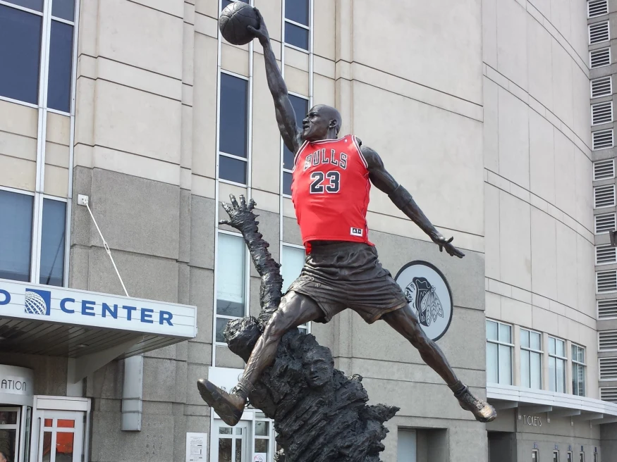 iron statue of Michael Jordan wearing a Chicago Bulls jersey in front of a stadium entrance