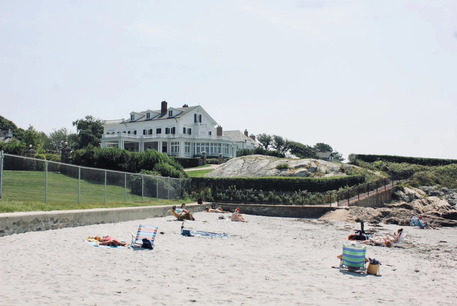 Beachgoers relaxing on the beach in front of mansion on a summer day in Newport, Rhode Island.