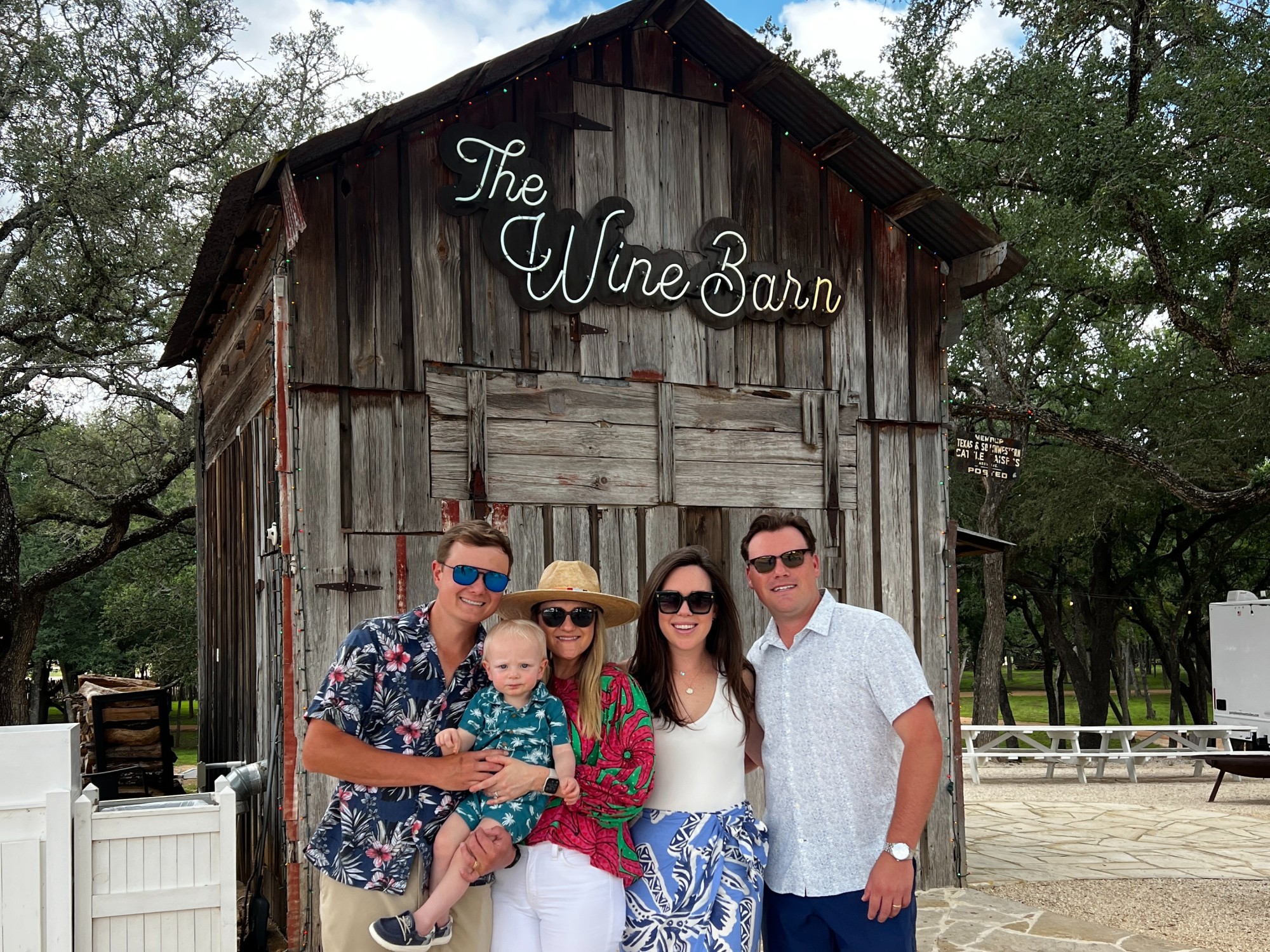 Two men, two women and a kid posing in front of Wine Barn.