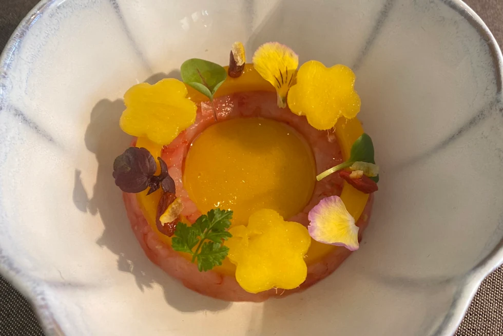 Beautifully presented pastry with flowers on a white plate.
