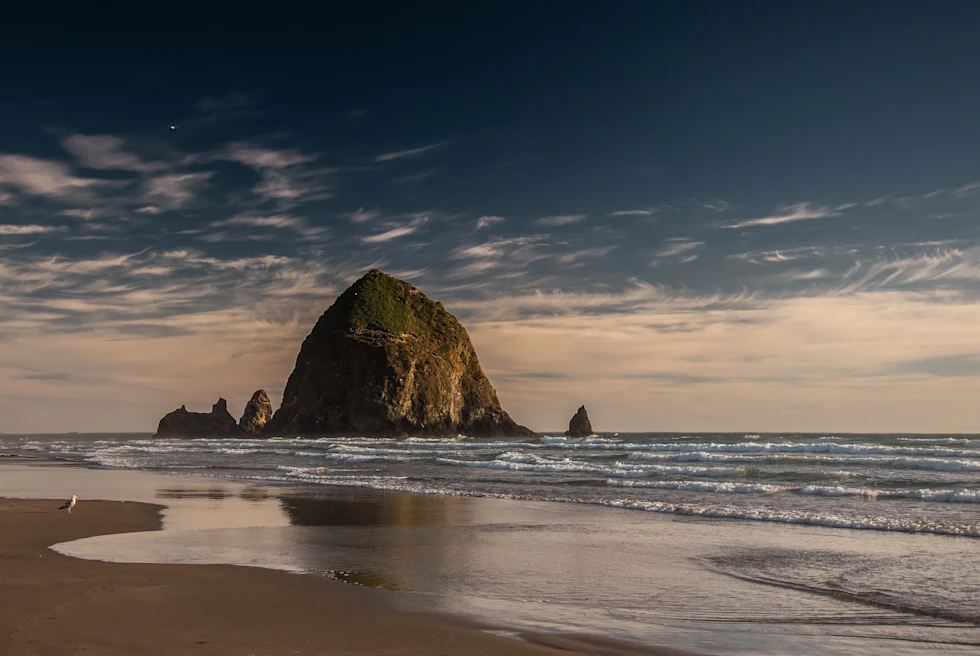 large rock in body of water next to beach
