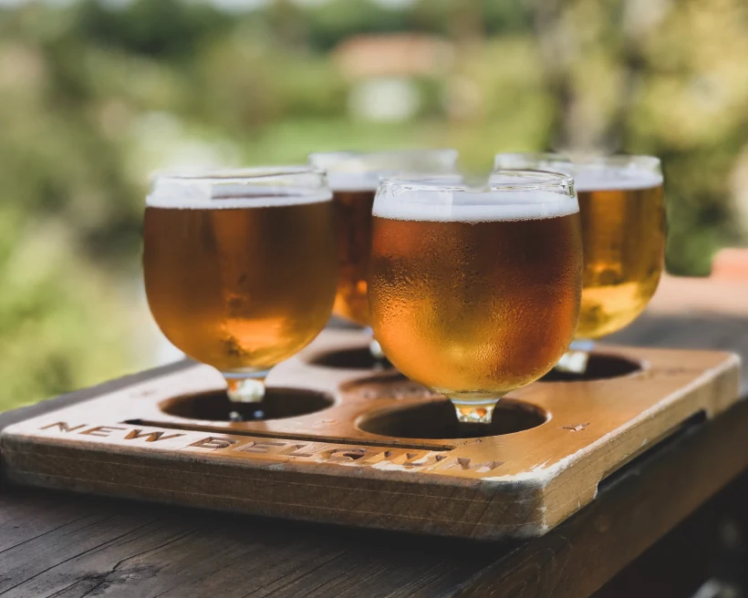 four glasses filled with beer on a wooden table during daytime