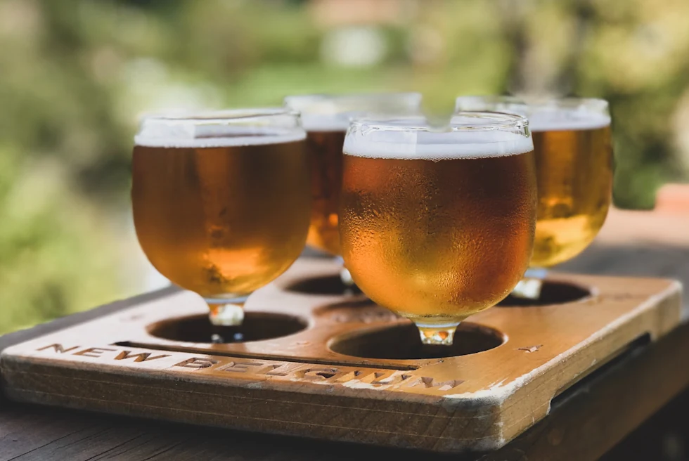 four glasses filled with beer on a wooden table during daytime