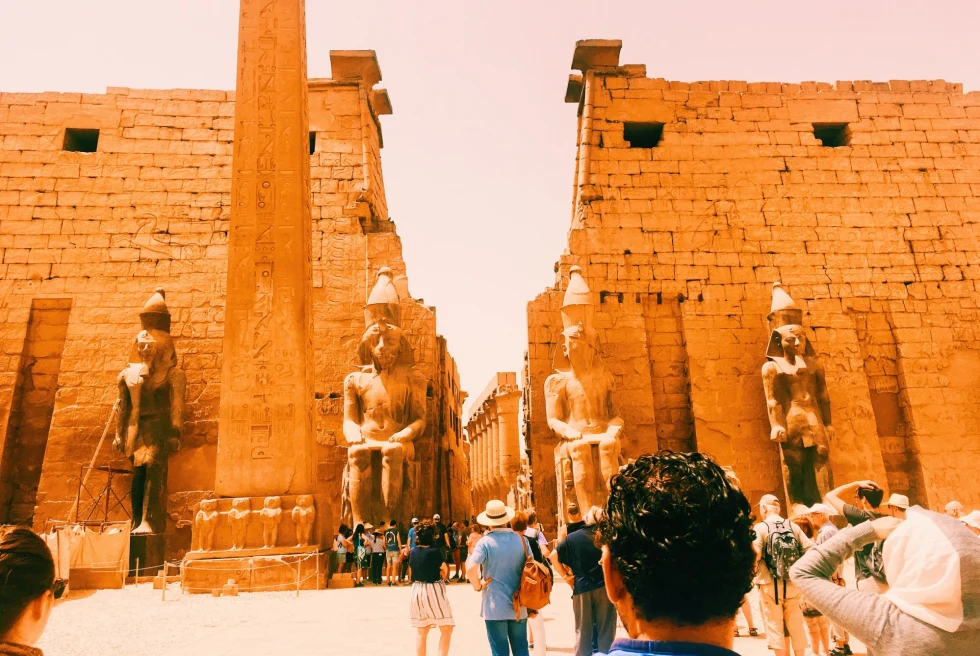 ancient ruins in a desert with large sculptures at the entrance