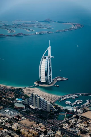 An aerial view of the Burj Al-Arab, Dubai and surrounding ocean and city taken during daytime