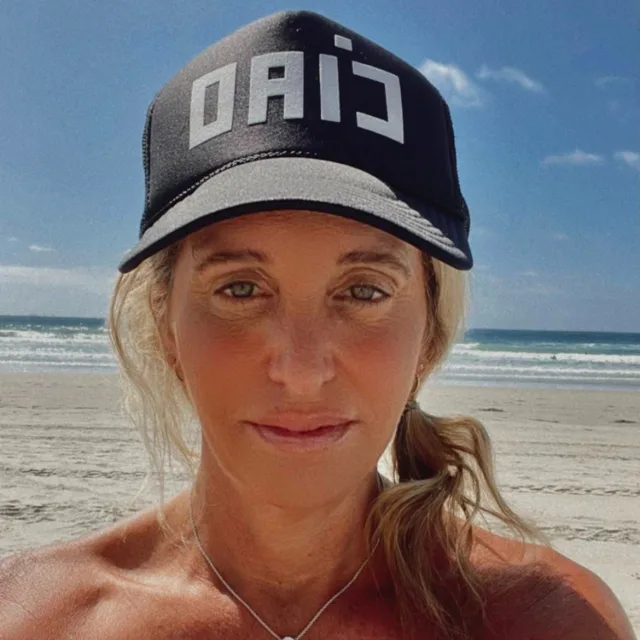 Travel advisor Jennifer Trotti O'Brien on a beach wearing peacock cap with a writing CIAO on it.