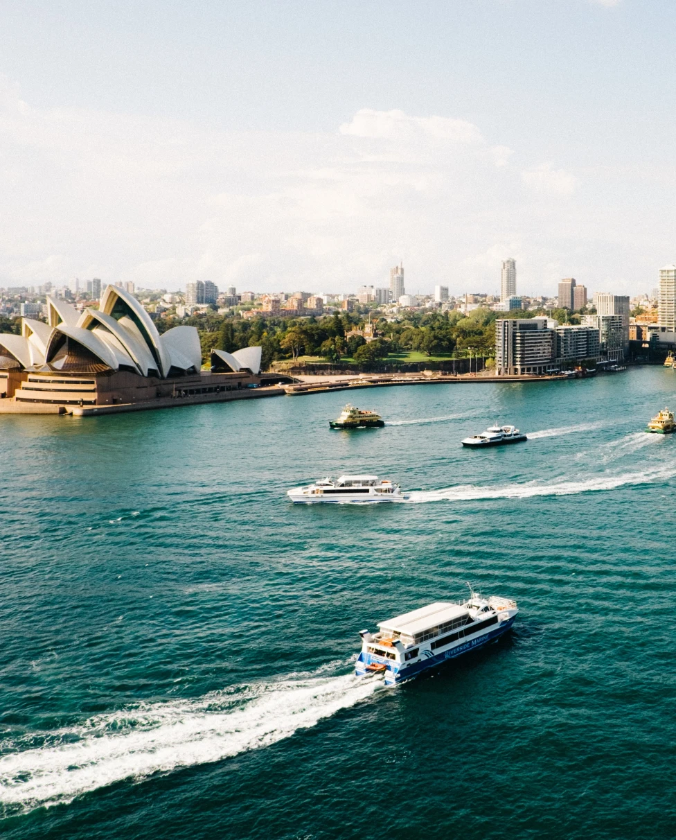 A skyline of Sydney with sea, boats and buildings.