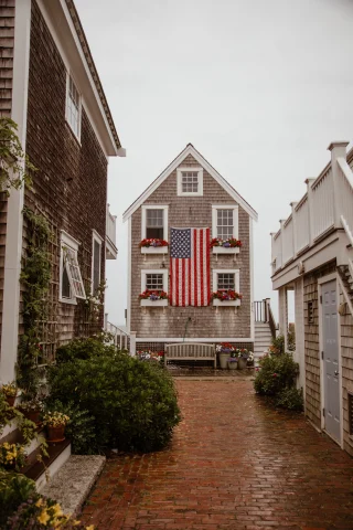 Brick alley lined with houses and American flag hanging on cloudy day