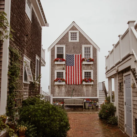 Brick alley lined with houses and American flag hanging on cloudy day