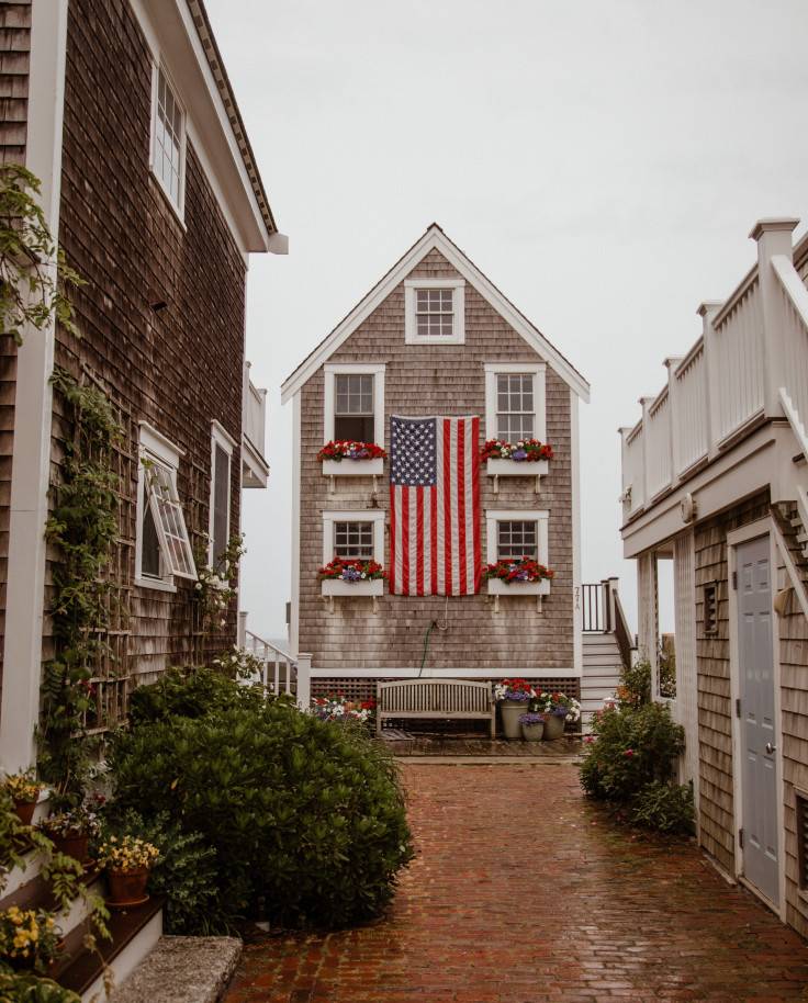 Brick alley lined with houses and American flag hanging on cloudy day