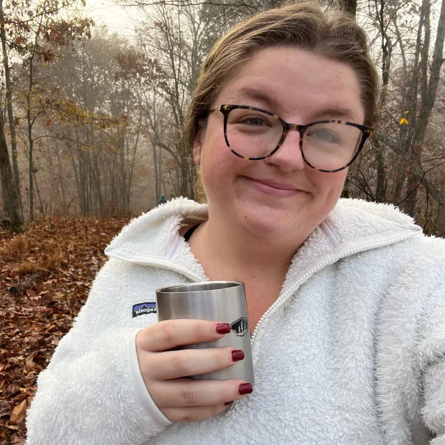 Travel Advisor Snow White holding a silver cup in front of the woods.
