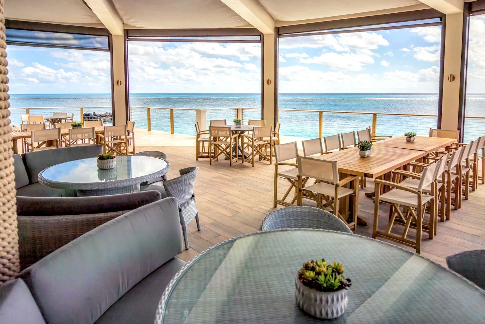 An outdoor restaurant under a balcony just beside the sea. 