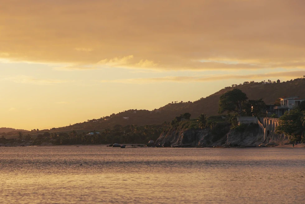 Body of water at golden hour with hills at the back.