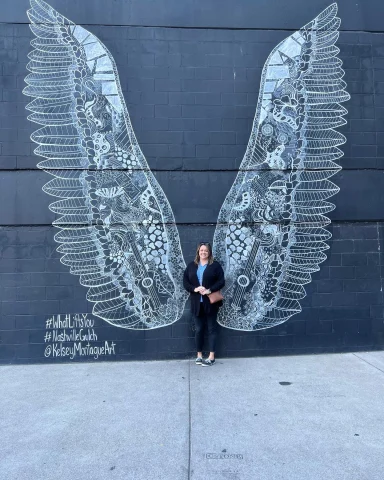 Wings wall art with a woman standing in front of it.