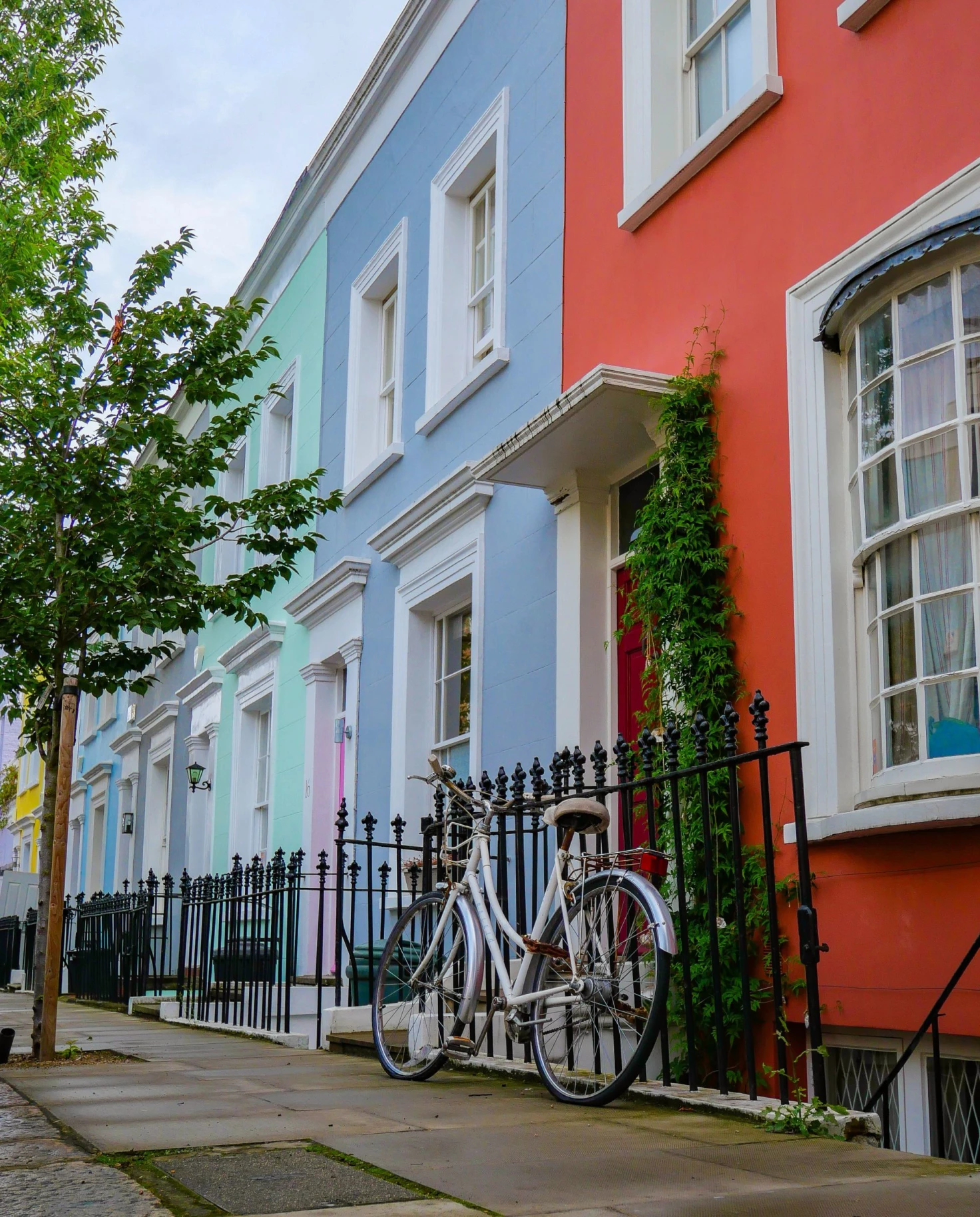 pastel and bright colored houses and a bicycle leans on the wrought iron fence