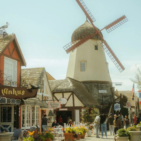 windmill and buildings with people walking during daytime