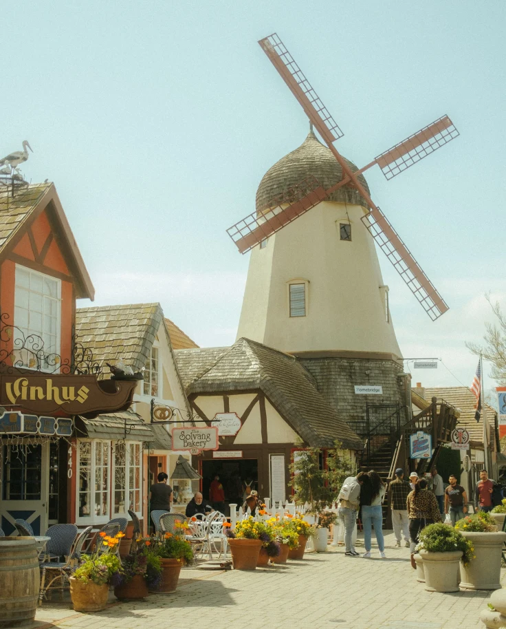windmill and buildings with people walking during daytime
