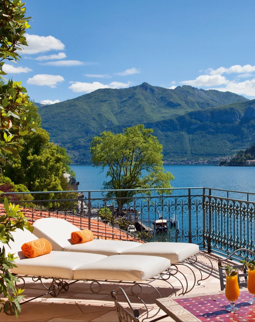 two lounge chairs on a terrace overlook a lake on a sunny day