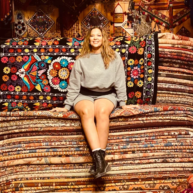 Travel Advisor Carol McKnight sits atop a pile of traditional carpets.