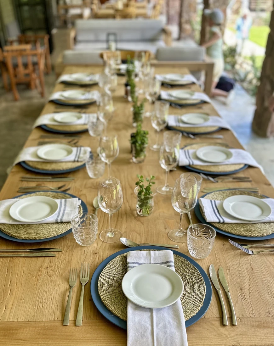 A view of a long wooden table set for multiple people with beautiful centerpieces. 