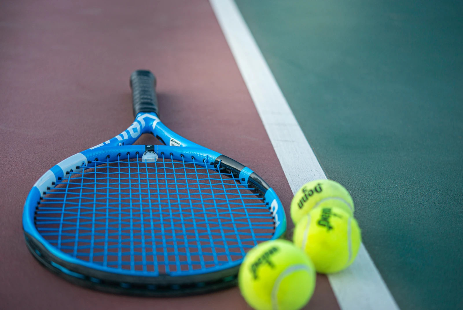 blue tennis racket on a court with two tennis balls