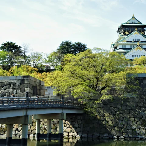 Castle in Osaka perched on hill with bridge in foreground