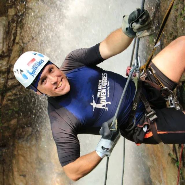 Travel Advisor Bill Cavalletto in a white helmet repelling down a waterfall.