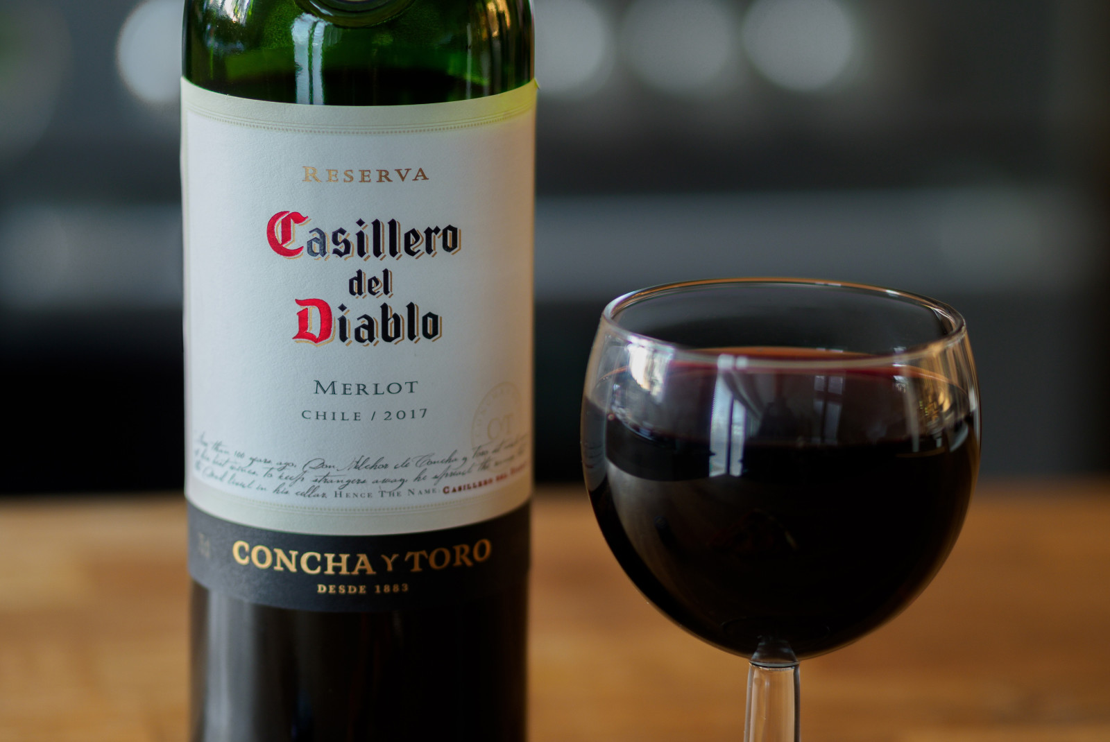 Bottle of wine with glass of red wine on wooden table