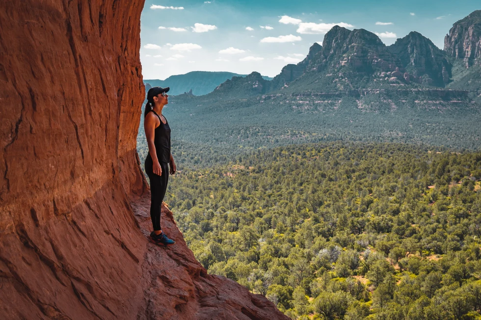 A woman standing on a red rock formation in Sedona, Arizona. 
