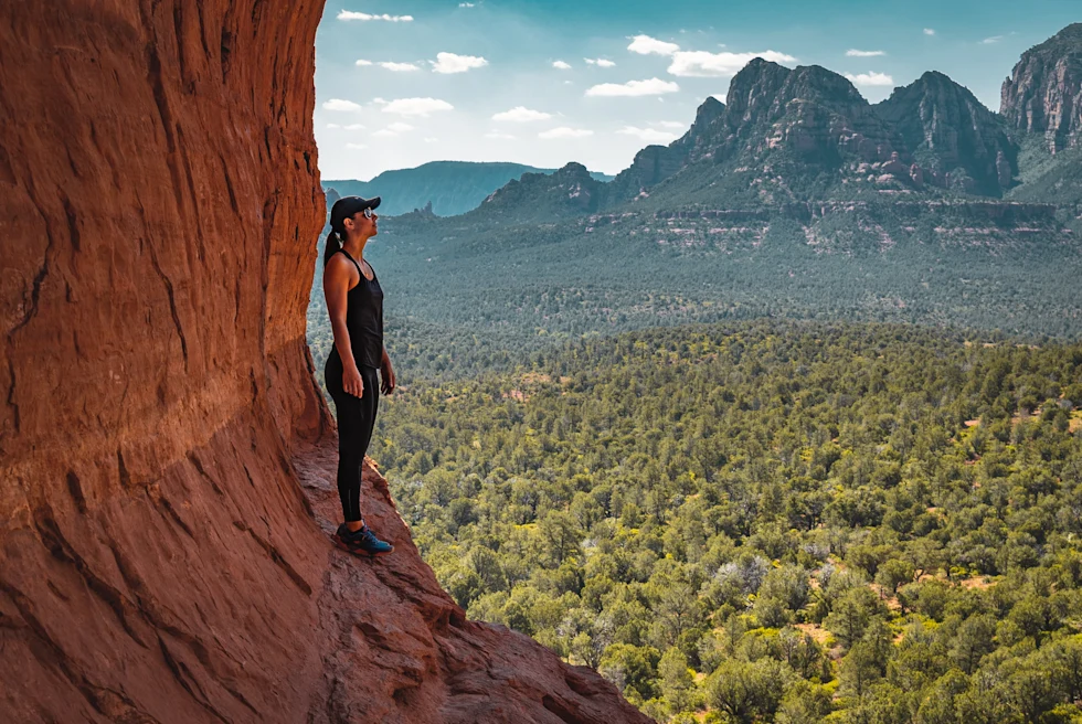A woman standing on a red rock formation in Sedona, Arizona.