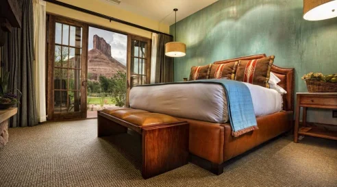 A room at the Gateway Canyons resort, with leather furniture, a green wall and a view of red rocks.