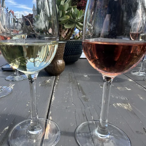 A picture of two wine glasses placed on a table during daytime.