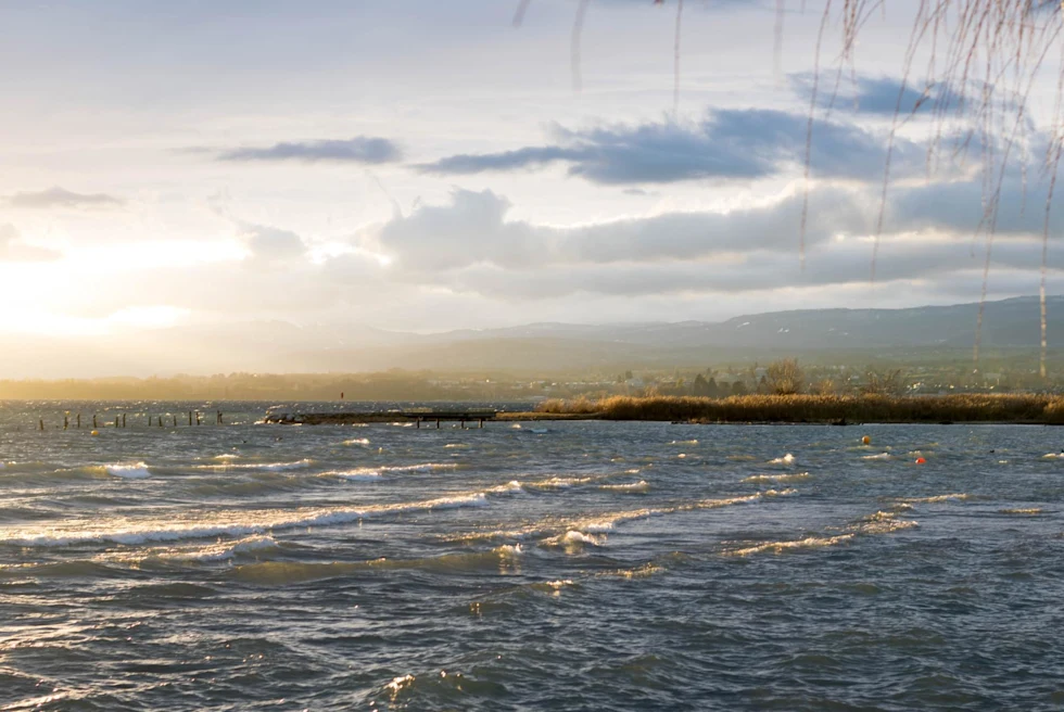 a lake at sunset with land in the distance