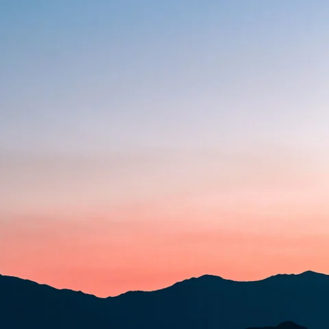 silhouette of a mountain range under a blue to pink sunset