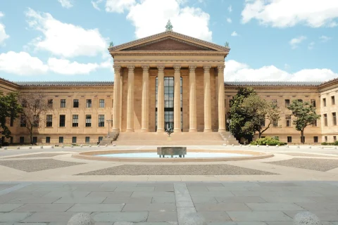 Philadelphia tan building with mountain and a fountain in front blue sky with white clouds