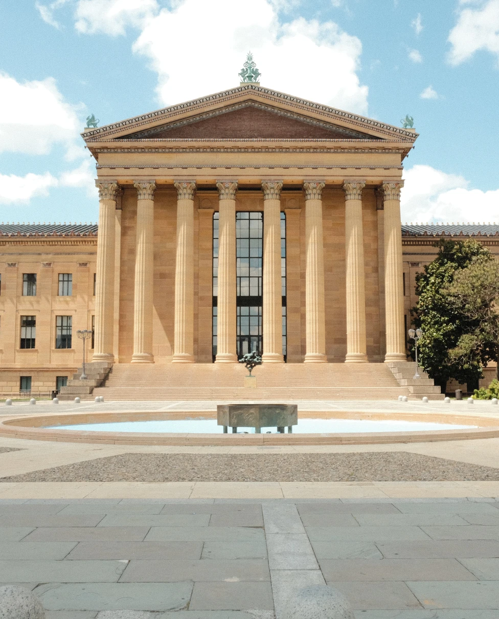 Philadelphia tan building with mountain and a fountain in front blue sky with white clouds