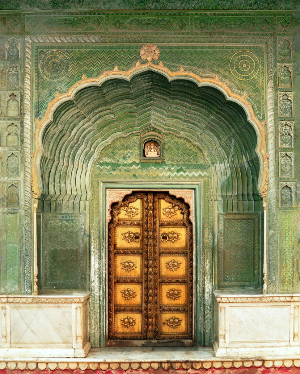 A picture of a wooden door of a green and gold colored wall.
