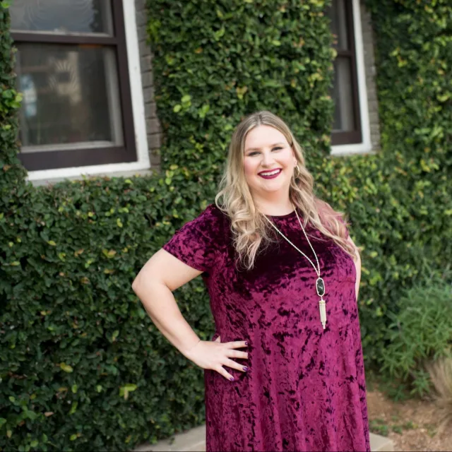 Travel Advisor Gillian Spatz in a purple dress outside house with green walls. 