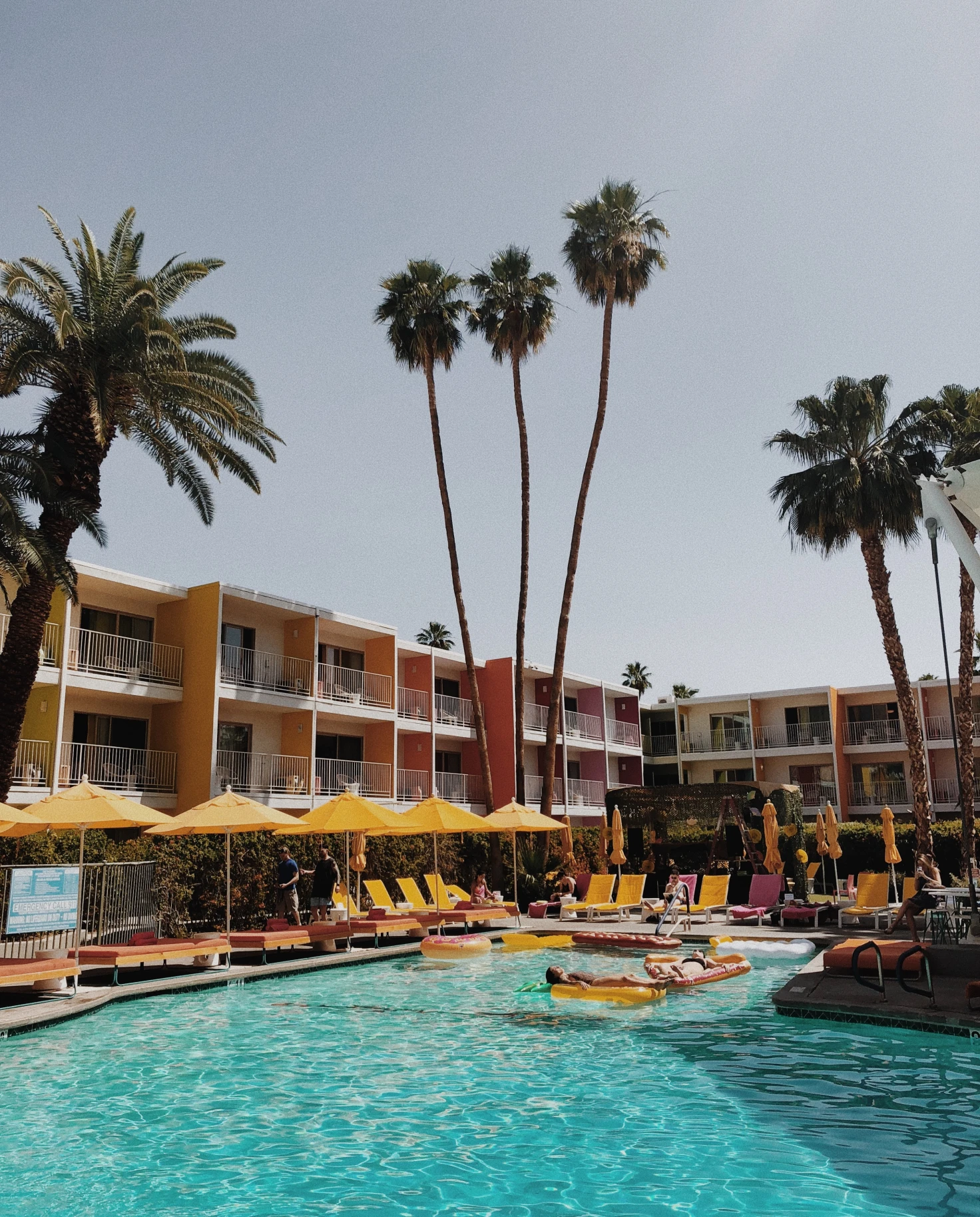 A hotel pool surrounded by yellow umbrellas in Palm Springs. 
