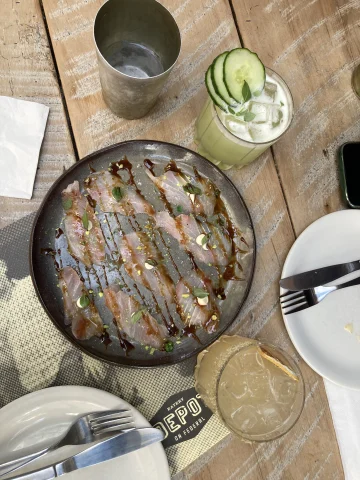 An aerial view of a fish dish at a restaurant with drinks on the table
