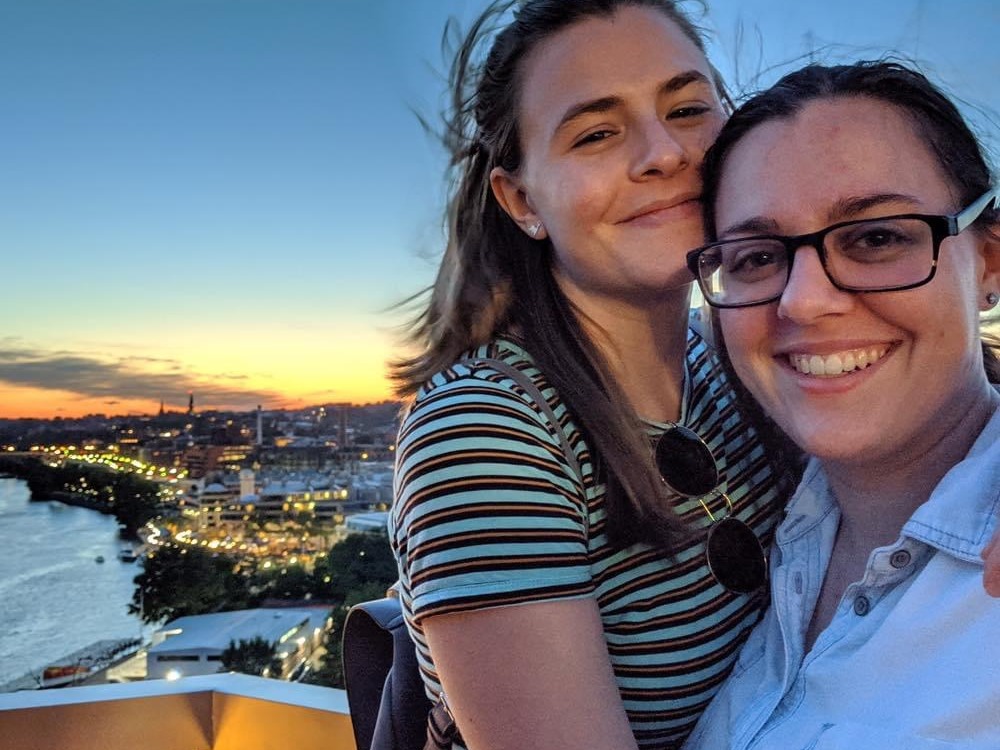 Two women on rooftop with city lights at the back during early evening.