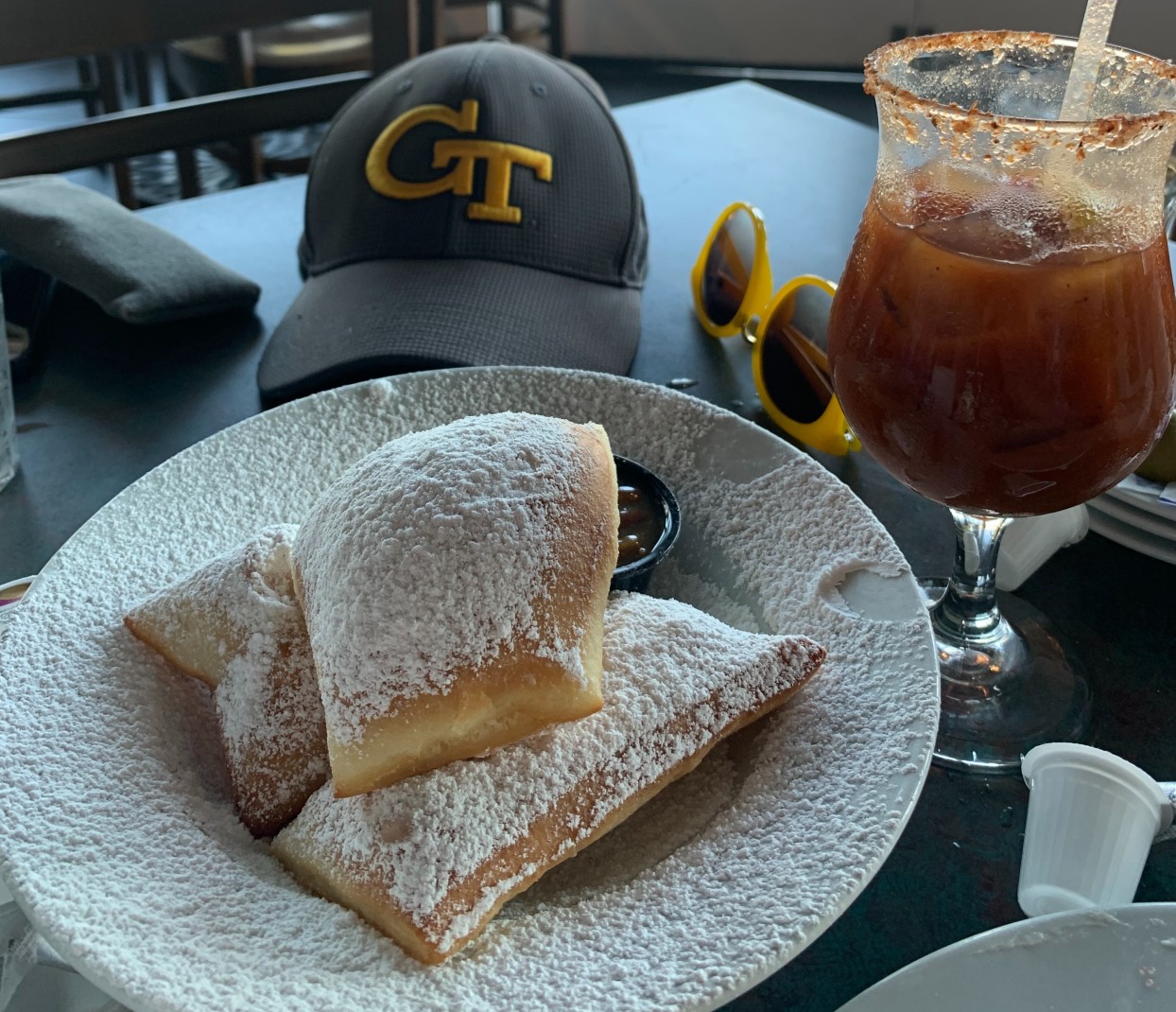 plate of beignets and a drink on a black table