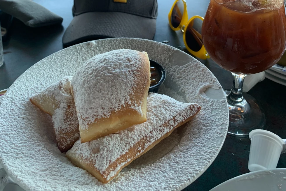 plate of beignets and a drink on a black table