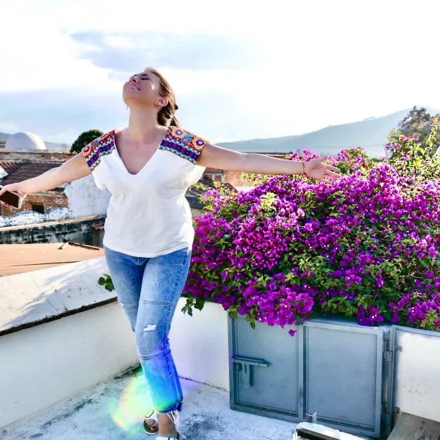 Travel Advisor Britt Wengel outside in jeans and a white top in front of purple flowers.