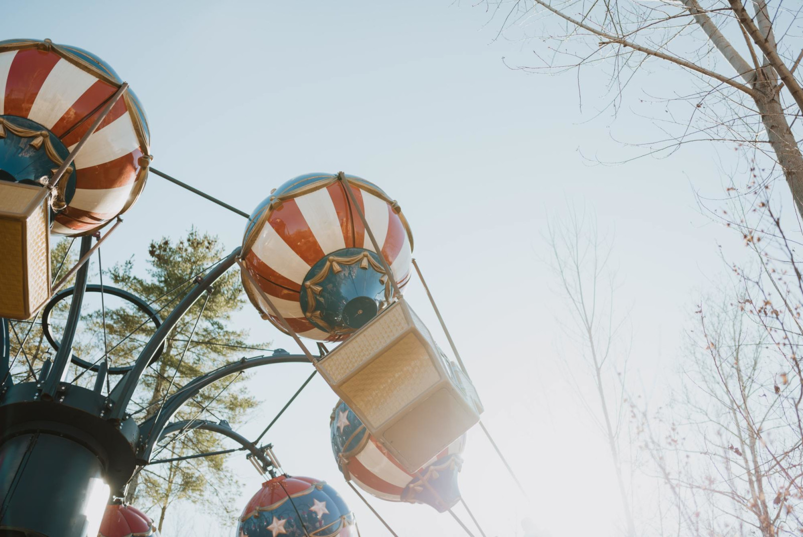 Rotating carnival balloon ride decorated with American colors on a bright day.