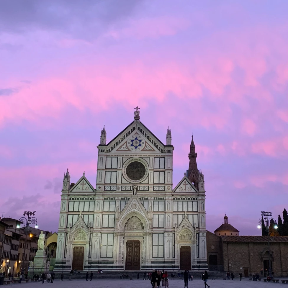 A picture of a church called Santa Croce taken in the evening with a purple sky in the background