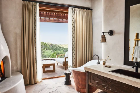 southwestern-style bathroom with a copper tub and lit fireplace